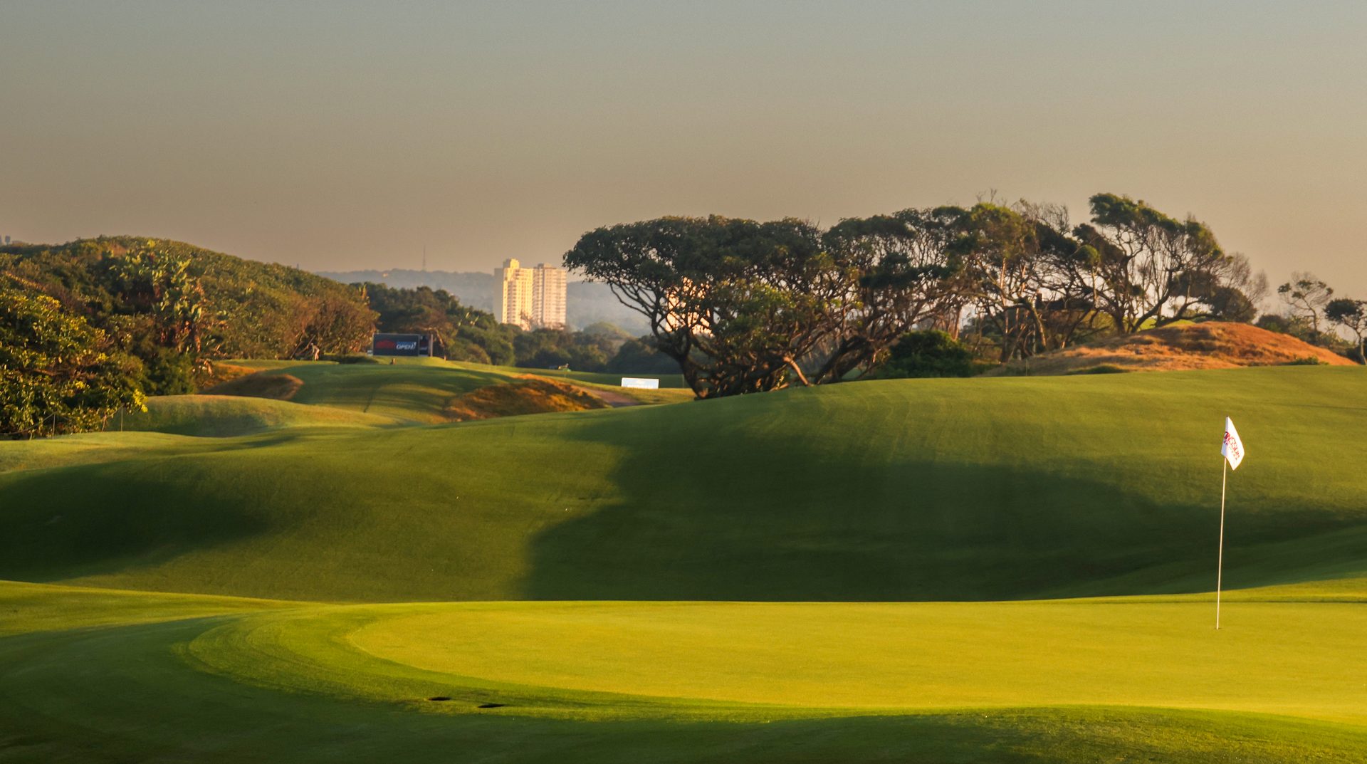 A green at golden hour with wind-shaped coastal trees, KwaZulu-Natal